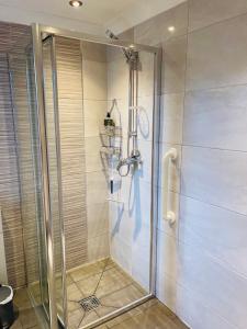 een douche met een glazen deur in de badkamer bij Cozy Bicester Village townhouse with garden in Bicester