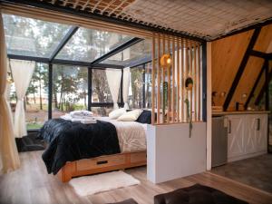 um quarto com uma cama num quarto com janelas em El Prado Glamping em Susudel  