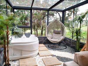 a room with a hammock and a chair in a greenhouse at El Prado Glamping in Susudel  