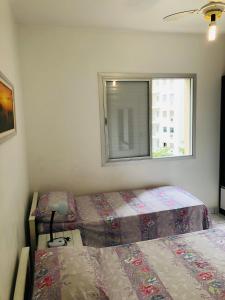 a bedroom with two beds and a window at Relax Pitangueiras Guarujá in Guarujá +24 photos