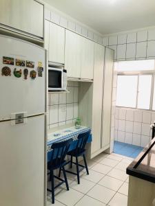 a kitchen with a refrigerator and a table with chairs at Relax Pitangueiras Guarujá in Guarujá