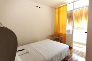 a small bedroom with a bed and a window at Hospedaje EL MARQUEZ Expat in Máncora