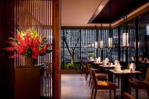 un restaurante con mesas y sillas y un jarrón de flores en Wulai Pause Landis Resort en Wulai
