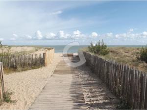 un camino de madera a la playa con una valla en Appartement La Tranche-sur-Mer, 3 pièces, 4 personnes - FR-1-357-12, en La Tranche-sur-Mer