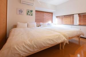 1 cama blanca grande en una habitación con ventanas en アブラハウス別府, en Beppu