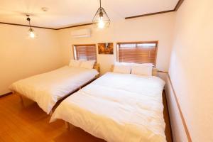 Dos camas en una habitación con sábanas blancas. en アブラハウス別府, en Beppu