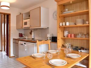 eine Küche mit einem Holztisch mit Tellern und Weingläsern in der Unterkunft Appartement Méribel, 2 pièces, 4 personnes - FR-1-180-378 in Les Allues
