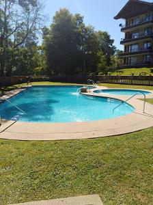 a large swimming pool in a yard with a building at CONDOMINIO LOS CASTAÑOS ALICURA, PUCÓN, departamento 2 dormitorios, 1 baño, estacionamiento, piscina in Pucón