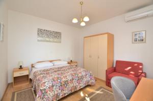 een slaapkamer met een bed en een rode stoel bij Apartment Gianfranko in Opatija