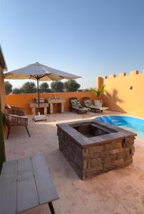 une terrasse avec un foyer extérieur en pierre et un parasol dans l'établissement Desert Inn Resort and Camp, à Ras al Khaimah
