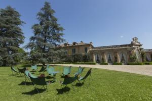 a group of chairs sitting in the grass in front of a house at Locanda Marchesi Alfieri in San Martino Alfieri