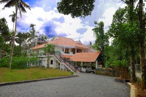 a white house with a red roof and a driveway at BEN COTTAGE in Thekkady
