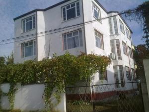 a white house with a fence in front of it at Prima Guest House 2 in Saints Constantine and Helena