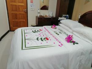 a white bed with a sign on it with flowers on it at ilaa Beach Maldives in Gulhi