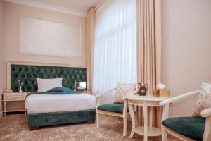 a bedroom with a bed and a table and a chair at al Madina Hotel Samarkand in Samarkand