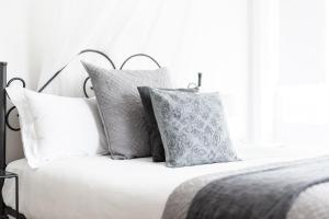 a white bed with gray pillows on it at The Woods Pokolbin in Pokolbin
