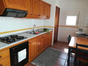 eine Küche mit Holzschränken, einer Spüle und einem Herd in der Unterkunft Acogedora casa de pueblo en Beniarbeig - Alicante Alma in Beniarbeig