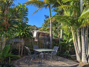 a table and chairs in a garden with palm trees at Sail Inn Motel in Yeppoon