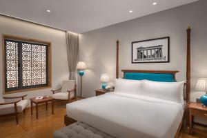 普杰Time Square Resort & Spa Bhuj的卧室里有一张白色的大床和一把椅子