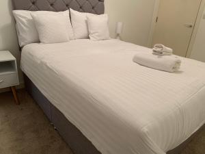 ein großes Bett mit weißen Laken und Handtüchern darauf in der Unterkunft Centra St albans city 2bedRoom 2 shower ROOM APT free parink in St Albans