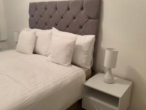 ein weißes Bett mit grauem Kopfteil und einem Nachttisch in der Unterkunft Centra St albans city 2bedRoom 2 shower ROOM APT free parink in St Albans