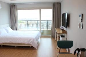 a bedroom with a bed and a large window at Haemorat Pension in Seogwipo