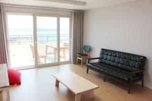 a living room with a black leather couch and a table at Haemorat Pension in Seogwipo