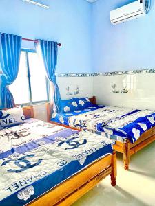 2 aparte bedden in een slaapkamer met blauwe muren bij NHÀ NGHỈ TÂM AN in Châu Thành