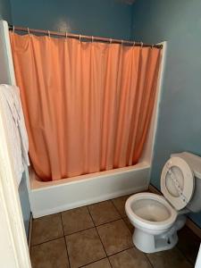 - un rideau de douche orange dans la salle de bains pourvue de toilettes dans l'établissement Deluxe Inn LA, à Los Angeles