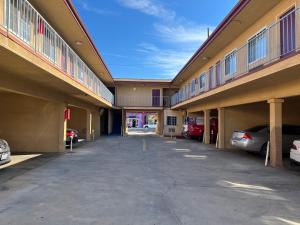 un grand bâtiment avec des voitures garées dans un parking dans l'établissement Deluxe Inn LA, à Los Angeles
