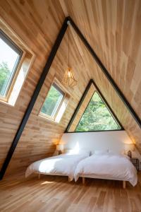 2 Betten in einem Loft-Schlafzimmer mit einem großen Fenster in der Unterkunft A-Frame House Minami Karuizawa - Vacation STAY 58046v in Karuizawa
