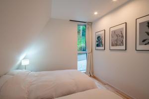 a white bedroom with a bed and a window at A-Frame House Minami Karuizawa - Vacation STAY 58046v in Karuizawa