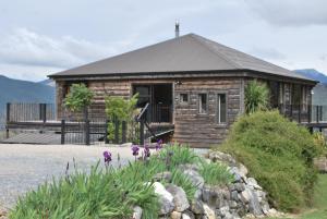 a log cabin with a porch and flowers in front of it at Kea Ridge Lodge in Kairuru