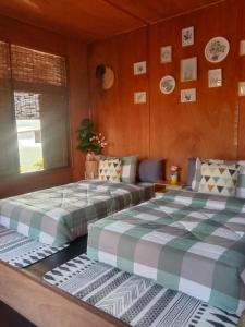 two beds in a room with wooden walls at Sweet Home Floating House in Ban Lum Le
