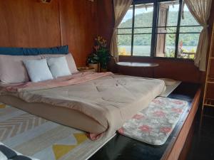ein großes Bett in einem Zimmer mit Fenster in der Unterkunft Sweet Home Floating House in Ban Lum Le