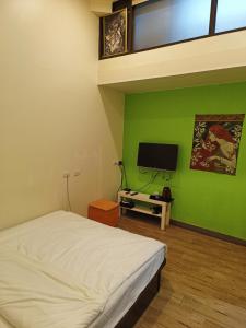 1 dormitorio con cama blanca y pared verde en 路邊望海 en Jiufen