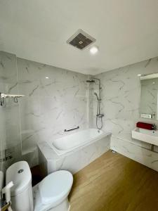 a white bathroom with a toilet and a bath tub at Platinum Yellow Bandung Villa 24 Pax Private Pool in Bengkok