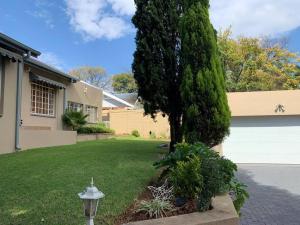 una casa con un grande albero nel cortile di Cheerful 3-bedroom home indoor & outdoor fireplace a Johannesburg