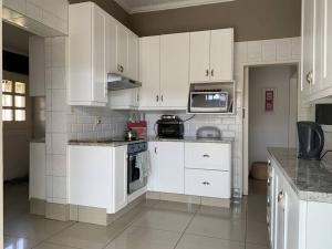 una cucina con armadietti bianchi ed elettrodomestici bianchi di Cheerful 3-bedroom home indoor & outdoor fireplace a Johannesburg