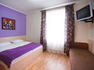 a bedroom with a bed and a tv and a window at Gala Hotel in Kamianets-Podilskyi