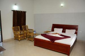 ein Schlafzimmer mit einem Bett und zwei Stühlen darin in der Unterkunft Maravakandy Farm and Guest House in Masinagudi