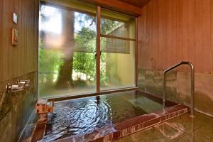 a bath tub in a room with a window at Sanyo-so in Izunokuni