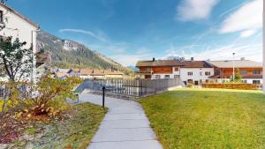 a sidewalk leading to a yard with houses and a fence at Family Apartment Sot Lantsch-Lenzerheide for 6 persons in Lenz