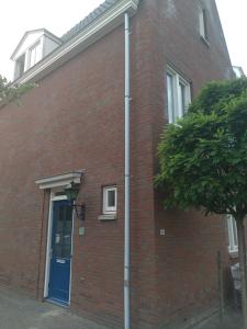 a brick building with a blue door and a tree at etage met slaap, en badkamer in Sommelsdijk