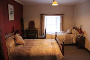 Craignure Inn في كريغنور: غرفة نوم بسريرين ونافذة