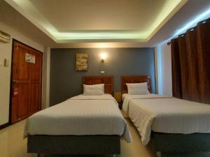 two beds in a hotel room with twoermott at Graphic House @ Chiang Rai in Chiang Rai