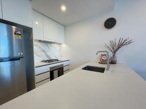 cocina blanca con fregadero y nevera en Lovely 2 Beds Apt with City View at South Brisbane, en Brisbane