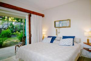 a bedroom with a white bed with blue pillows at Villa Cap Malheureux in Cap Malheureux
