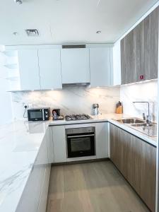 a white kitchen with white cabinets and a microwave at STAY Sensational 3BR Holiday Home near BurjKhalifa in Dubai