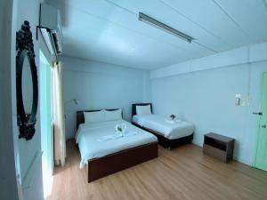 a white room with two beds and a mirror at T.U.B. Mansion in Nonthaburi